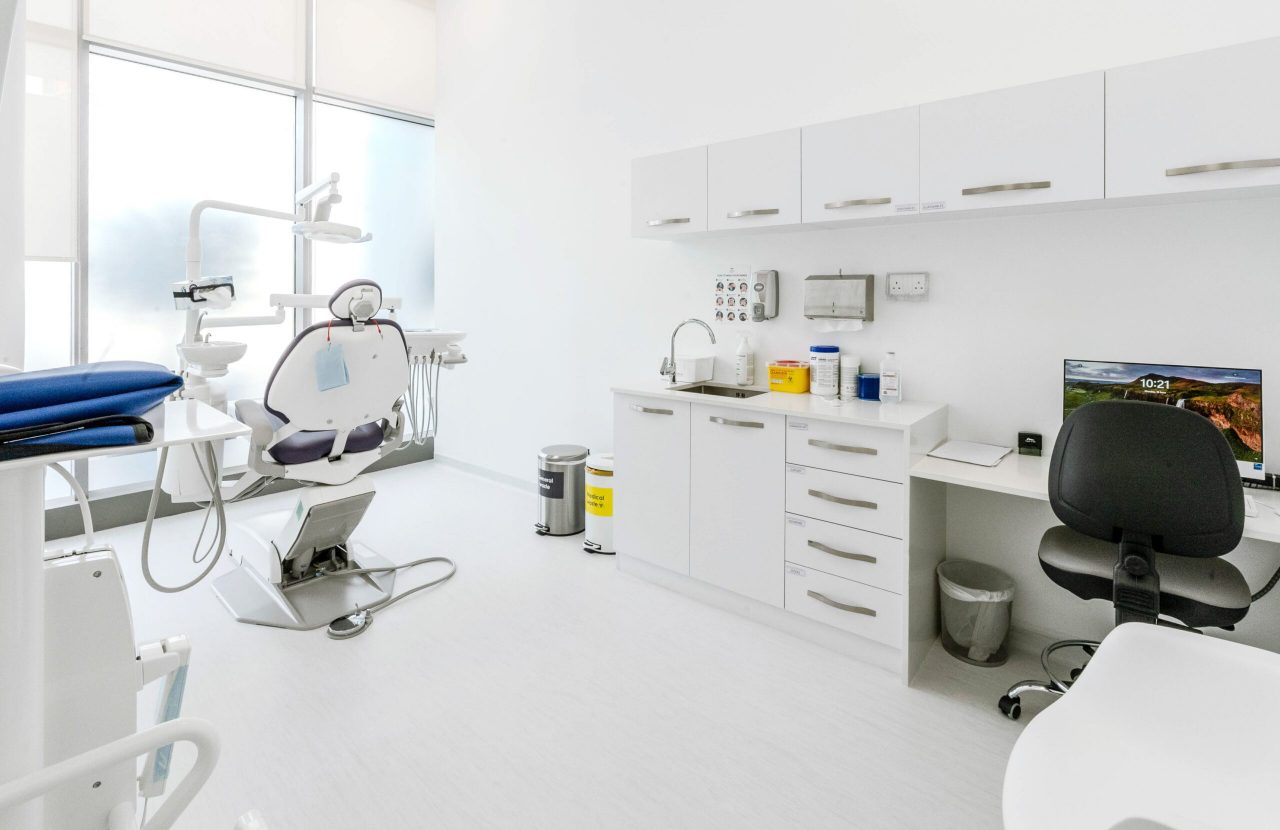 Dental treatment room at Regal Polyclinic with treatment chair, white service joinery and full-height glazing