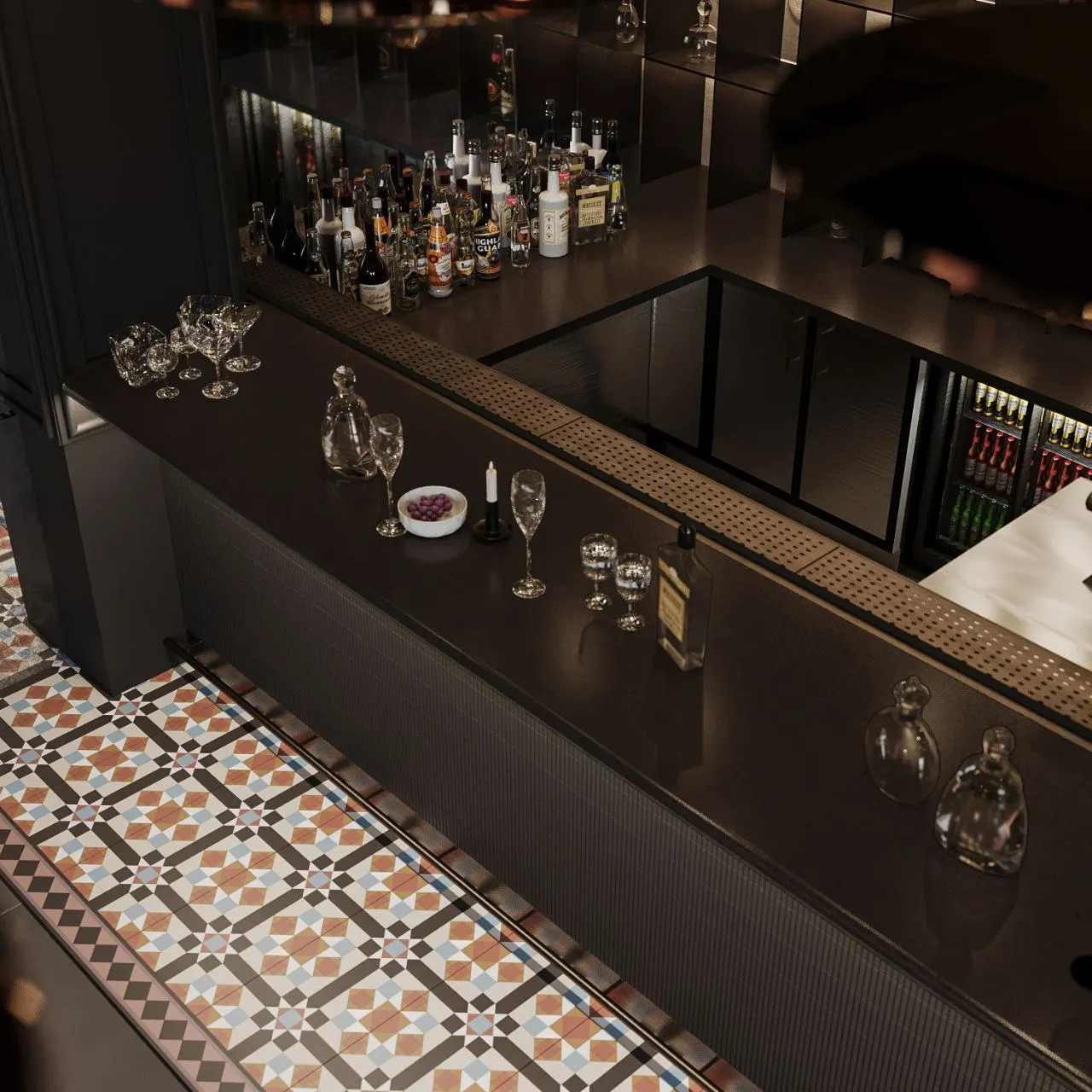 Overhead detail of the bar counter with glassware, perforated bronze drainer and patterned cement tile floor
