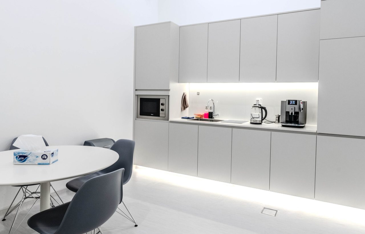 Staff pantry and breakout at Regal Polyclinic with handleless grey joinery, integrated appliances and a round meeting table