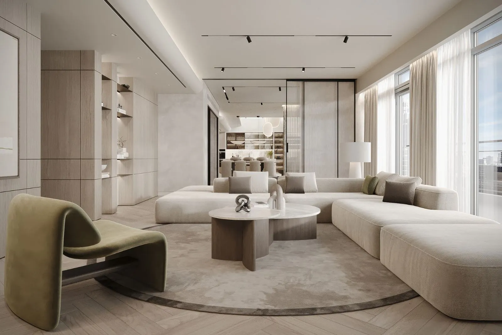 Open-plan living room with a long curved sand sofa, olive velvet lounge chair, travertine coffee tables and a sightline through to the kitchen and dining