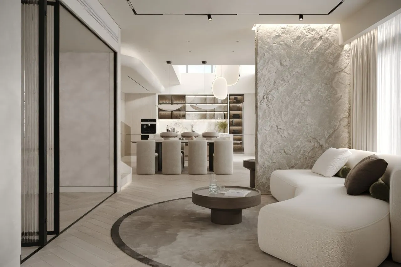 Formal sitting room with a split-face stone pier lit from above, a white curved sofa, round timber coffee table and reeded glass slider