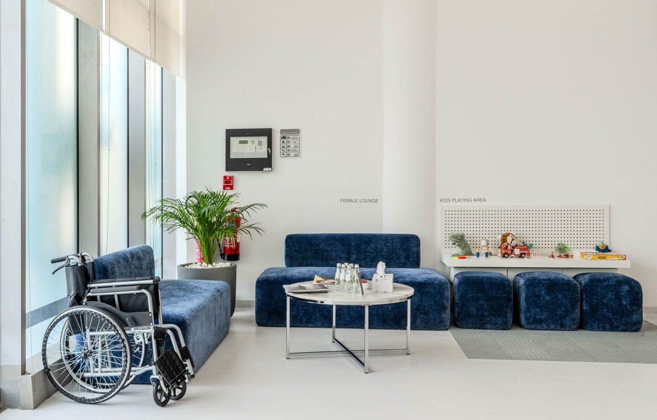 Female lounge at Regal Polyclinic with blue seating and a marble table beside the kids playing area