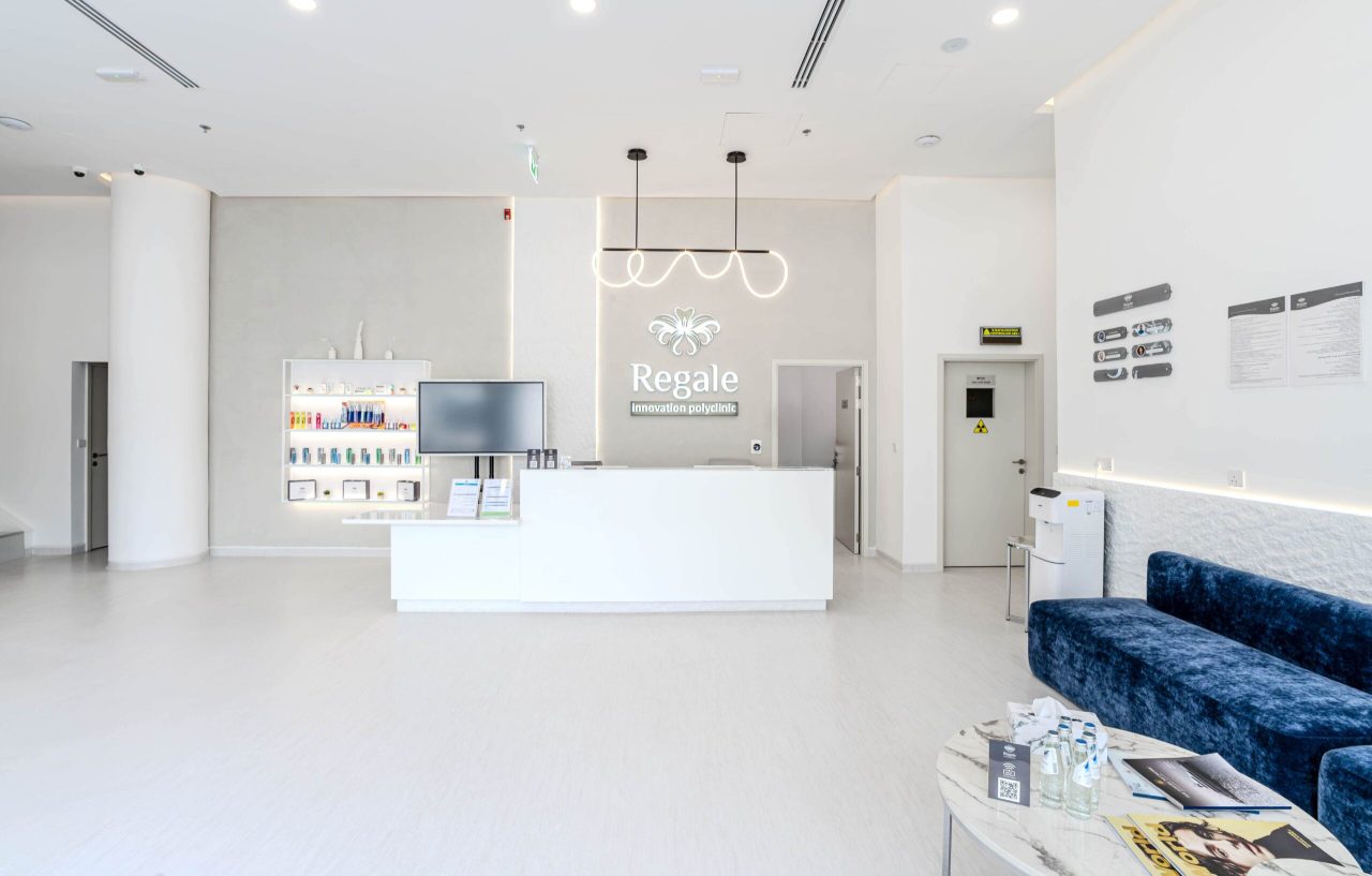 Regal Polyclinic reception desk in Business Bay, Dubai, with illuminated brand signage, ribbon pendant light and backlit display shelving