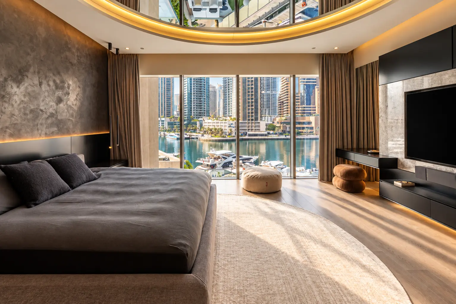 Master bedroom with a curved mirrored ceiling cove, plaster feature wall, black media unit and full-height glazing onto the marina and yachts