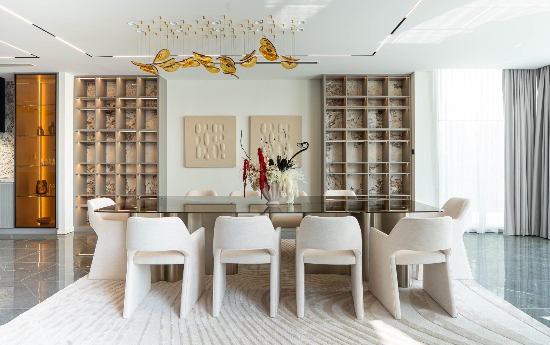 Formal dining room with amber glass chandelier and marble-backed shelving