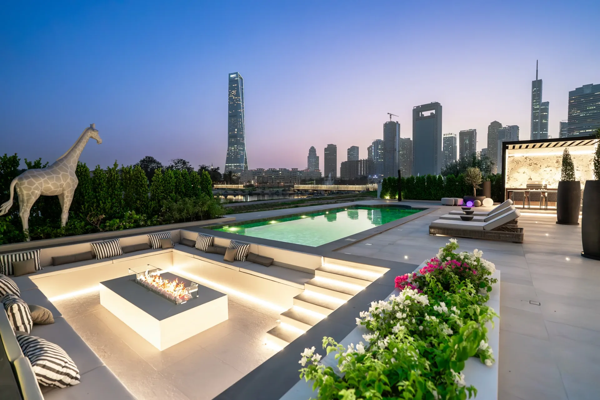 Pool and sunken fire-pit lounge at dusk with skyline