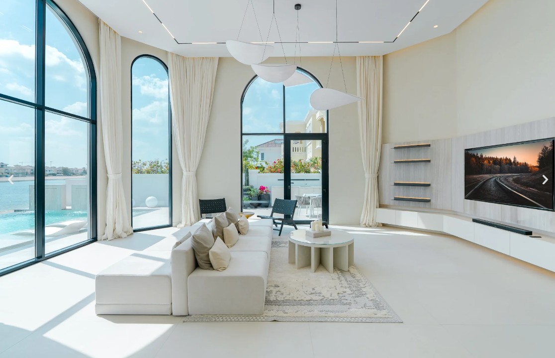 Double-height living room with arched windows and pool view