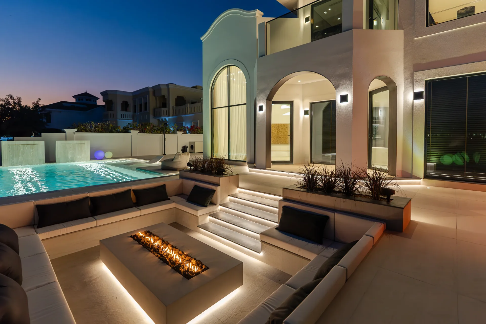 Resort-style pool and sunken fire-pit lounge at dusk