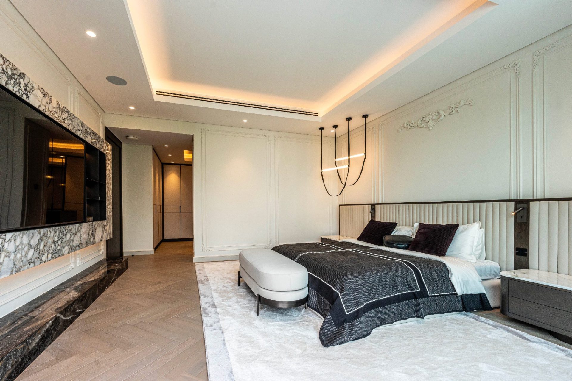 Principal bedroom with panelled walls and marble media wall