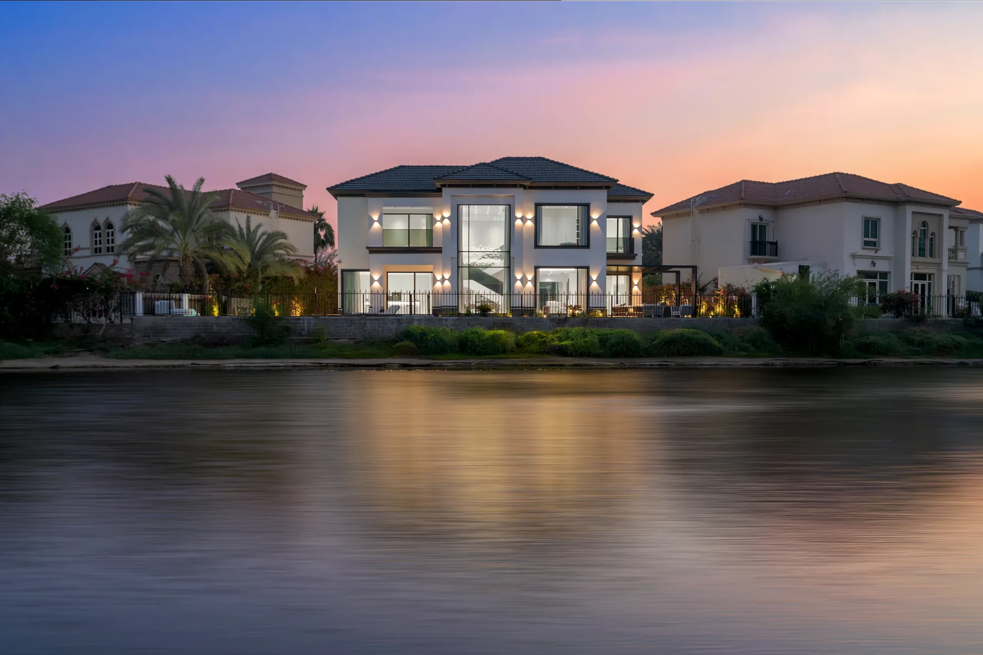 Lakefront villa illuminated at dusk reflected in the water