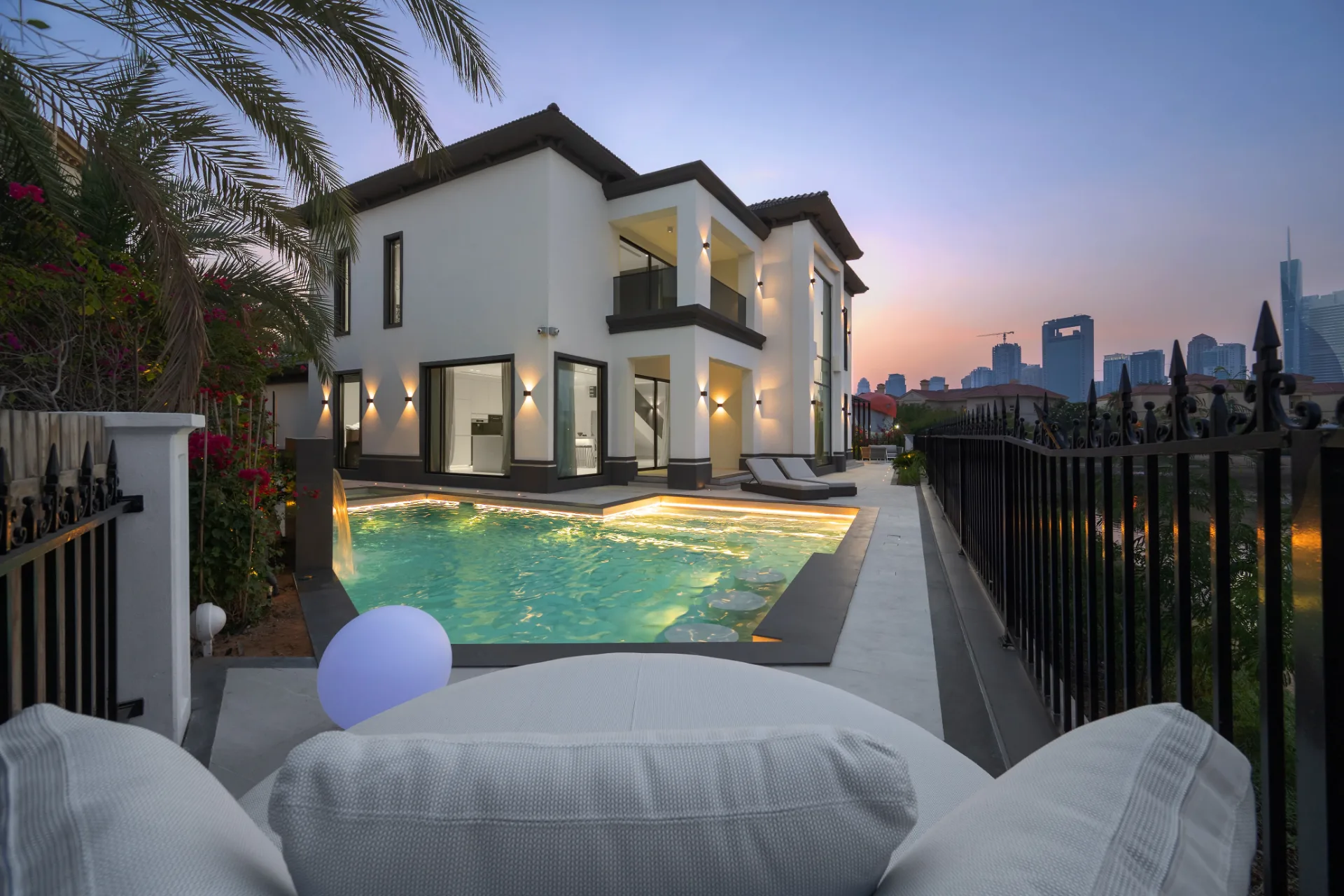 Lit pool and sunken lounge at dusk with city skyline