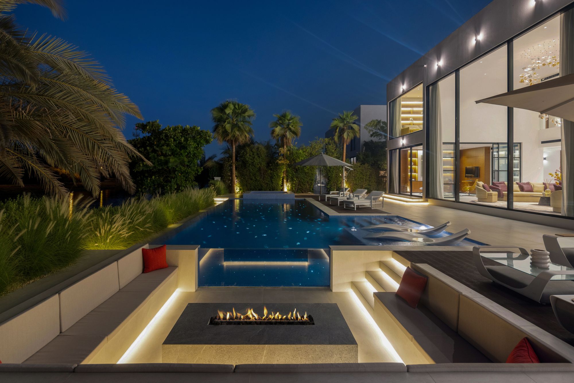 Sunken fire-pit lounge and pool at night