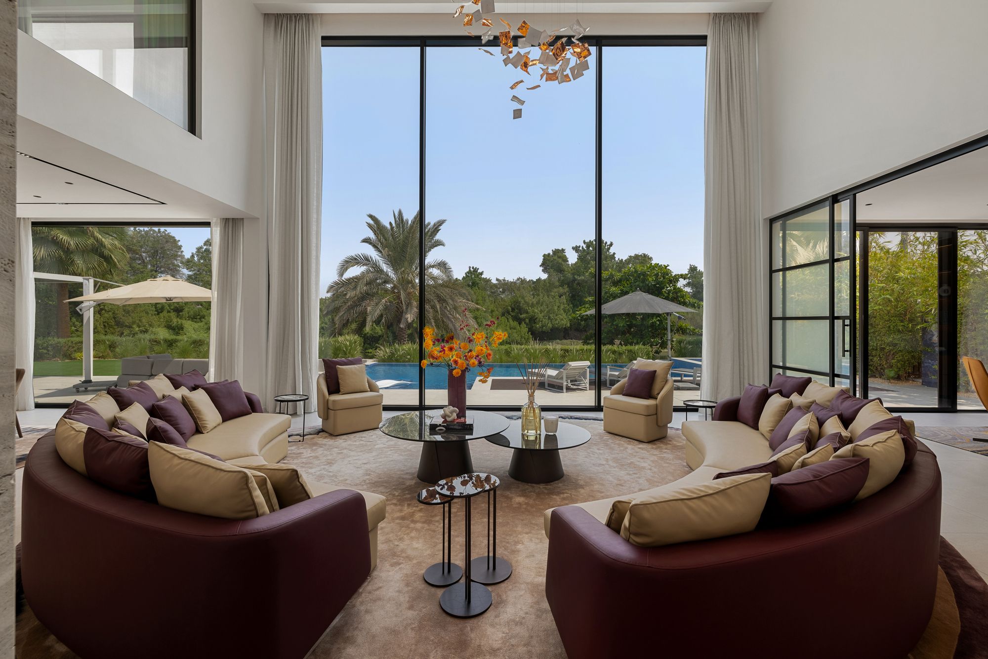 Double-height living room with floor-to-ceiling windows and pool view